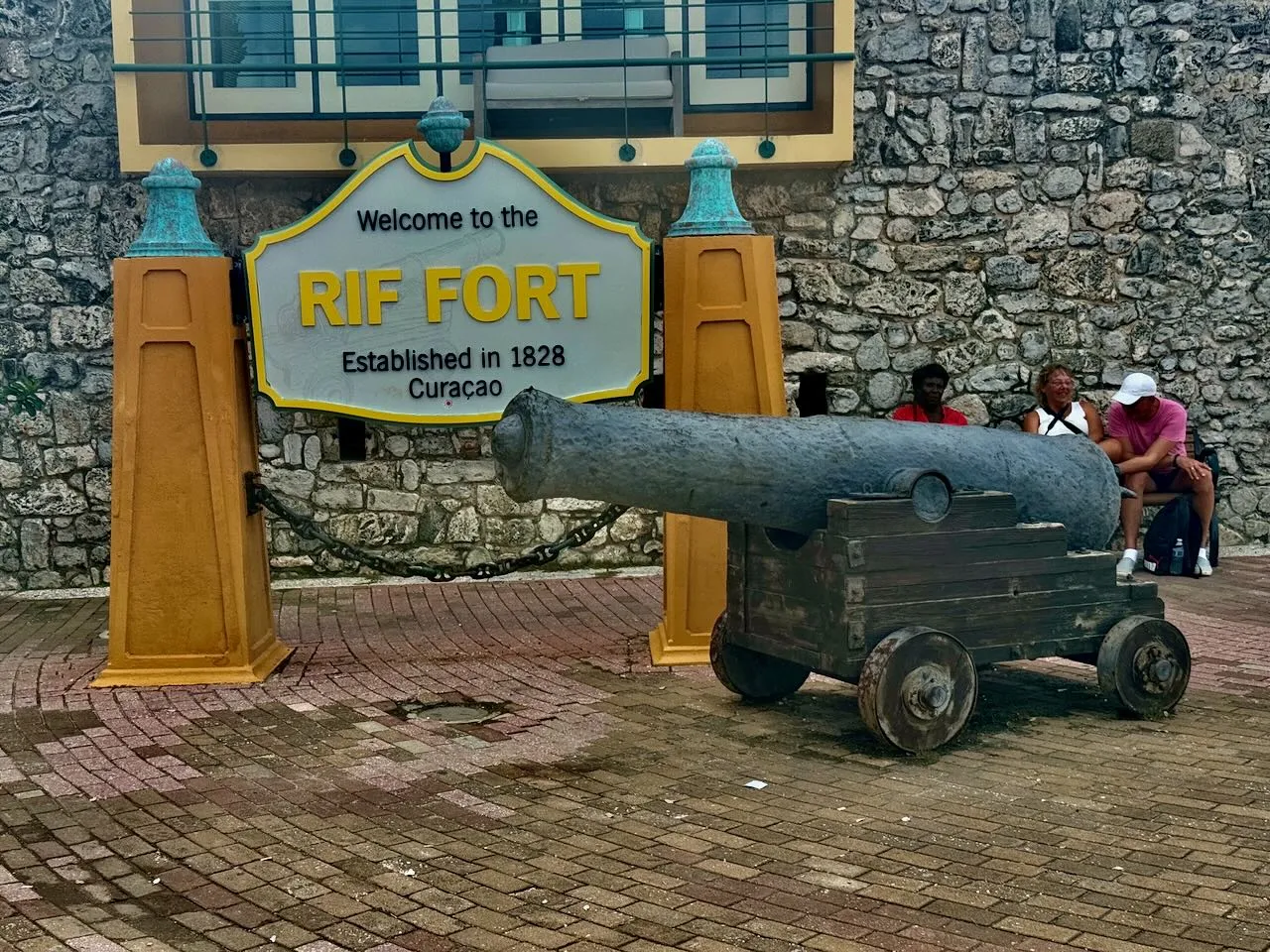 Rif Fort entrance with 'Welcome to the Rif Fort Established in 1828 Curacao' sign and historic cannon